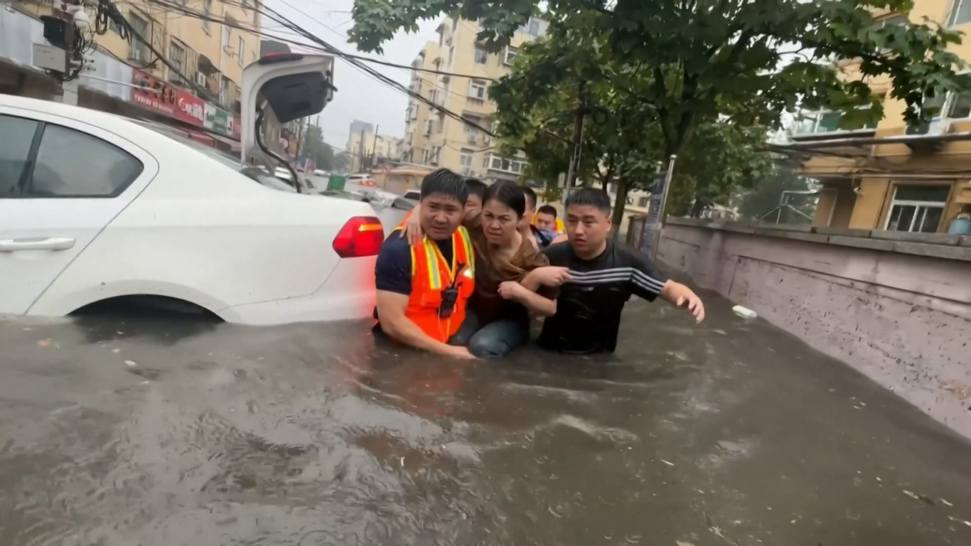 Petugas pemadam kebakaran sibuk melakukan operasi penyelamatan ketika hujan lebat masih mengguyur lokasi bencana untuk mengevakuasi orang-orang yang terjebak di dalam mobil dan daerah yang tergenang air di tengah banjir yang dipicu oleh badai di kota-kota Tiongkok utara dan timur